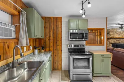 a kitchen with green cabinets and a stove top oven at Cabin 20- King Cabin w Roku TV Full Kitchen in Estes Park