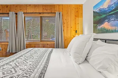 a bedroom with a white bed and two windows at Cabin 21- Accessible Unit & King Bed in Estes Park