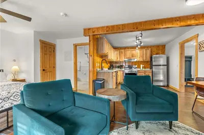 a living room with two chairs and a kitchen at Cabin 21- Accessible Unit & King Bed in Estes Park