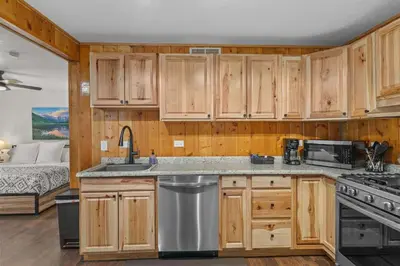a kitchen with wooden cabinets and a bed in a bedroom at Cabin 21- Accessible Unit & King Bed in Estes Park
