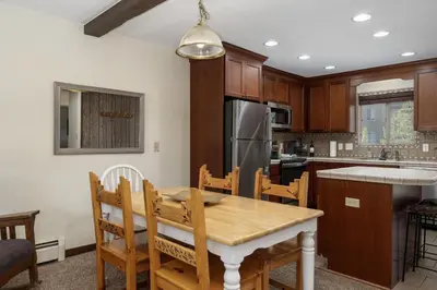 a kitchen with a wooden table with chairs and a refrigerator at Winter Park Condo with Fireplace, Centrally Located in Winter Park