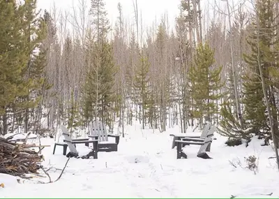three picnic benches in the snow in a forest at Rocky Mountain A Frame in Grand Lake