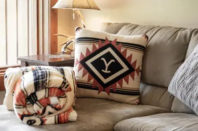 a couch with two pillows on it with a table at Luxury Lake Condo Walk to Downtown in Grand Lake