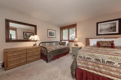 a bedroom with two beds and a dresser and a mirror at Luxury Lake Condo Walk to Downtown in Grand Lake