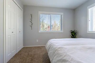 a white bedroom with a bed and two windows at Cute modern 2 bed retreat, a perfect basecamp in Fraser