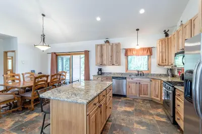 a kitchen with wooden cabinets and a table and a dining room at Spacious Pet-Friendly Grand Lake House in Grand Lake