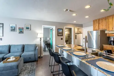 a kitchen and living room with a blue couch and a counter at Ski in ski out condo in Granby in Granby