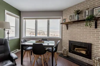 a dining room with a brick fireplace and a table and chairs at Ski in ski out condo in Granby in Granby