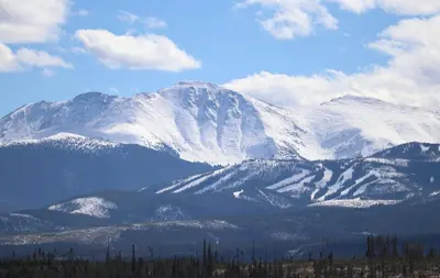 a mountain covered in snow with trees in the foreground at WP Top Floor Getaway in Winter Park