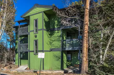 a green building with balconies and a tree at WP Top Floor Getaway in Winter Park