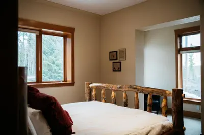a bedroom with a wooden bed with two windows at Scenic Mountain Retreat in Fraser in Granby