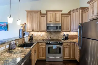 a kitchen with wooden cabinets and stainless steel appliances at Love Grand Lake Townhouse Pet Friendly With garage in Grand Lake