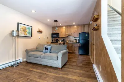 a living room with a couch and a kitchen at Winter Park Condo with Fireplace and Mountain Views in Winter Park