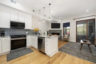 a kitchen with white cabinets and a fireplace at Cozy Grand Lake Hideaway Walk to Lake and Restaurants in Grand Lake