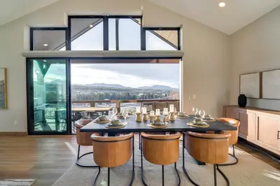 a dining room with a table and chairs and a large window at Luxe Home with Hot Tub, Close to Winter Park Resort! in Fraser