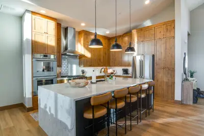 a kitchen with wooden cabinets and a large island with bar stools at Luxe Home with Hot Tub, Close to Winter Park Resort! in Fraser