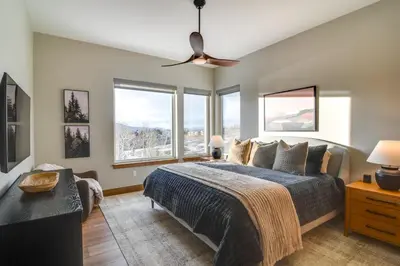 a bedroom with a bed and large windows at Luxe Home with Hot Tub, Close to Winter Park Resort! in Fraser