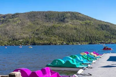 a row of green and pink paddle boats on a lake at Mad Moose Retreat Gorgeous Condo by Grand Lake in Grand Lake