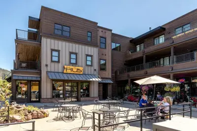 a patio with tables and chairs in front of a building at Mad Moose Retreat Gorgeous Condo by Grand Lake in Grand Lake