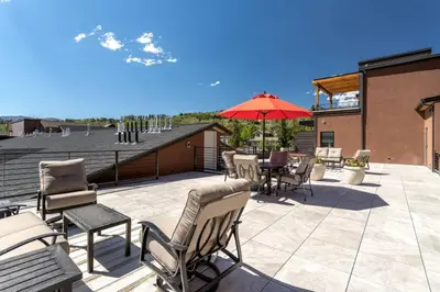 a patio with chairs and a table and an umbrella at Mad Moose Retreat Gorgeous Condo by Grand Lake in Grand Lake