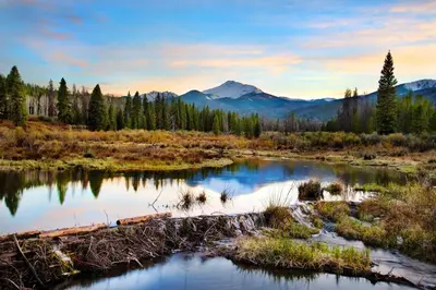 a river in a field with mountains in the background at 3 BR Private Mountain Retreat in Granby
