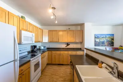 a kitchen with wooden cabinets and a white refrigerator at Central and Cozy Townhouse in Fraser