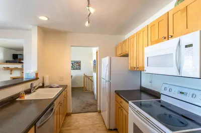 a kitchen with wooden cabinets and a white refrigerator at Central and Cozy Townhouse in Fraser