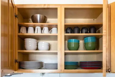 a cupboard with plates and bowls in it at Central and Cozy Townhouse in Fraser