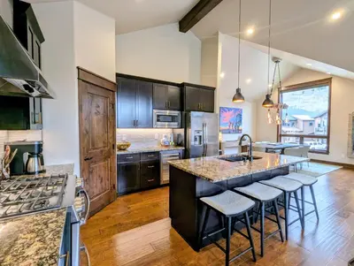 a kitchen with a large island with bar stools at River Run Townhomes 73 by SummitCove Lodging in Keystone