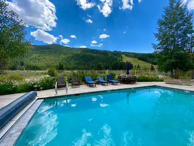 a swimming pool with chairs and a table and mountains at Red Hawk Lodge 2242 by SummitCove Lodging in Keystone