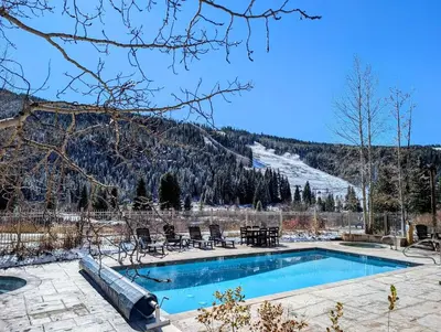 a swimming pool with chairs and a snow covered mountain at Red Hawk Lodge 2242 by SummitCove Lodging in Keystone