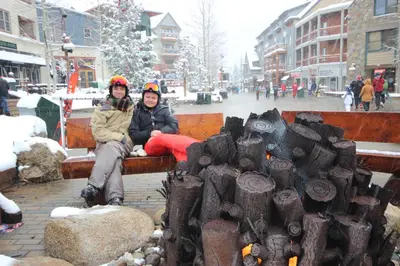 two people sitting on a bench next to a tree stump at Red Hawk Lodge 2242 by SummitCove Lodging in Keystone