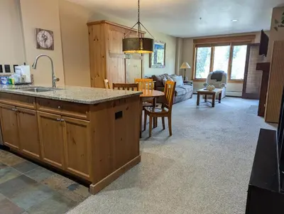 a kitchen and living room with a sink and a table at Springs 8886 by SummitCove Lodging in Keystone