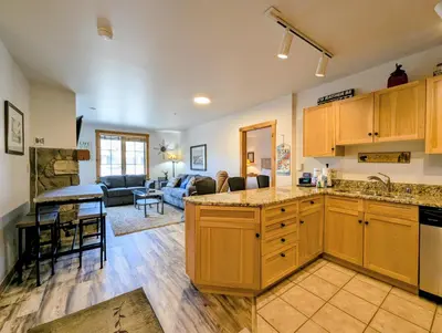 a kitchen with wooden cabinets and a living room at Dakota Lodge 8499 by SummitCove Lodging in Keystone