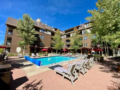 a swimming pool with chairs and a building at Dakota Lodge 8451 by SummitCove Lodging in Keystone