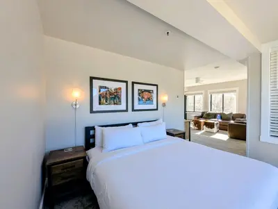 a bedroom with a large white bed and a living room at Slopeside 2793B by SummitCove Lodging in Keystone
