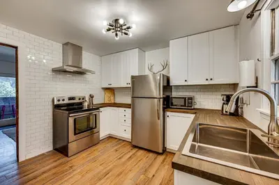 a kitchen with white cabinets and a stainless steel refrigerator at Mtn-View Retreat with Deck and Hot Tub in Estes Park! in Estes Park