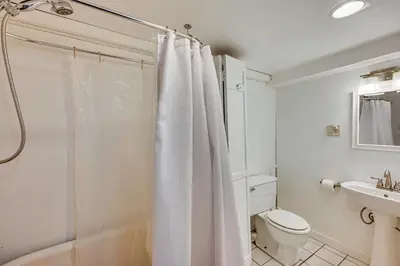a white bathroom with a shower curtain and a toilet at Mtn-View Retreat with Deck and Hot Tub in Estes Park! in Estes Park