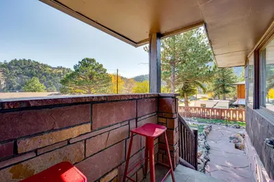 a red stool sitting on a brick balcony with a window at Mtn-View Retreat with Deck and Hot Tub in Estes Park! in Estes Park