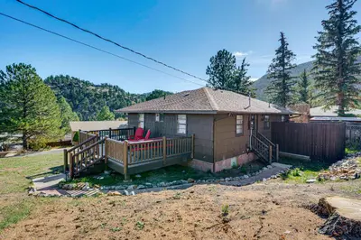 a small house with a porch and two red chairs at Mtn-View Retreat with Deck and Hot Tub in Estes Park! in Estes Park