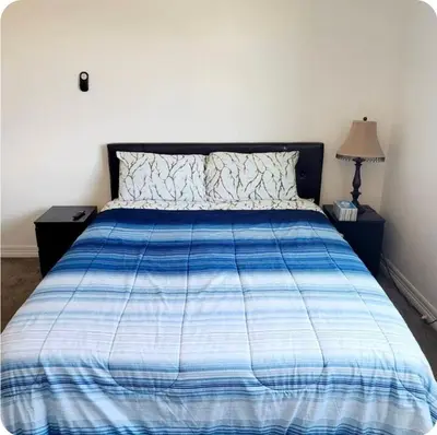 a bed with a blue and white comforter in a bedroom at Sweet stay near Denver airport in DEN