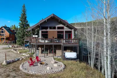 a house on a hill with red chairs in front of it at Ski Inn Condo condo in Winter Park