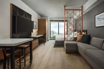 a living room with a couch and a desk at Apiary Hotel Belleview Station in Denver