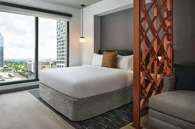 a bedroom with a bed and a large window at Apiary Hotel Belleview Station in Denver