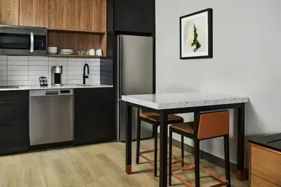 a kitchen with a table and two chairs and a refrigerator at Apiary Hotel Belleview Station in Denver