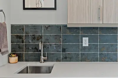 a kitchen with a sink and a tiled wall at Modern Retreat - Close to Old Town in Fort Collins