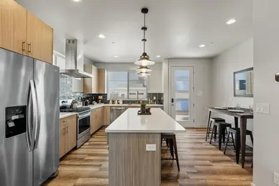 a kitchen with a stainless steel refrigerator and a table at Modern Retreat - Close to Old Town in Fort Collins