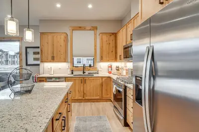 a kitchen with wooden cabinets and a stainless steel refrigerator at Walk to Ski Shuttle and Brewery! New Fraser Condo in Fraser
