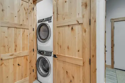 a washer and dryer in a room with wooden walls at Walk to Ski Shuttle and Brewery! New Fraser Condo in Fraser