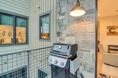 a porch with a tv and a stone wall at Walk to Ski Shuttle and Brewery! New Fraser Condo in Fraser
